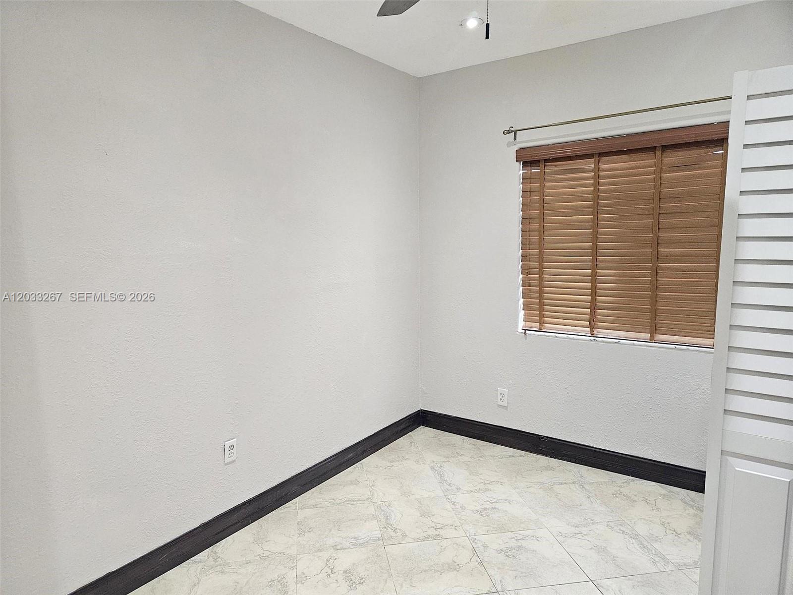 A room with light gray walls, dark baseboards, tiled flooring, and a window with blinds — 12975 SW 189th St # 1, Miami FL 33177, MIAMI, FL