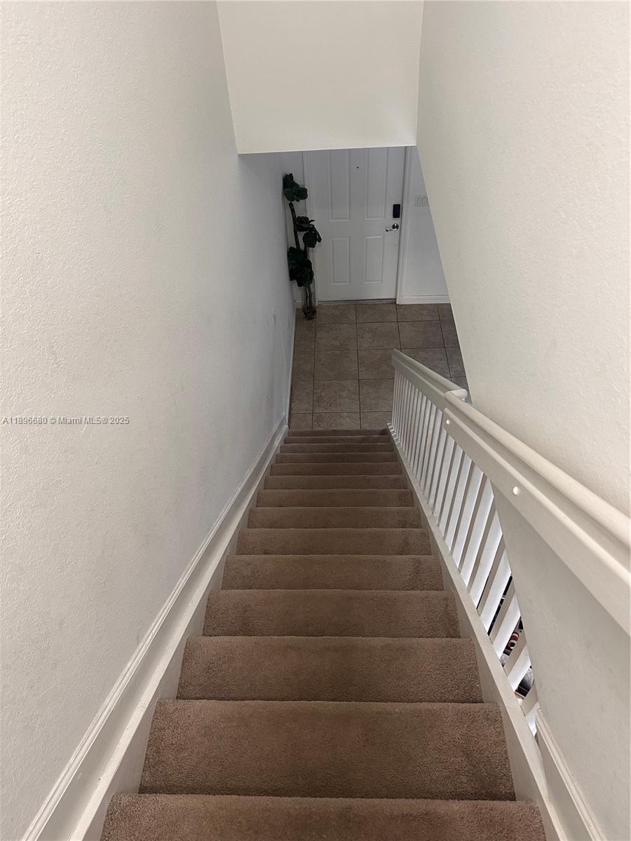 A carpeted staircase leads down to a tiled entryway with a white front door — 8867 W 35th Way, Hialeah FL 33018, HIALEAH, FL