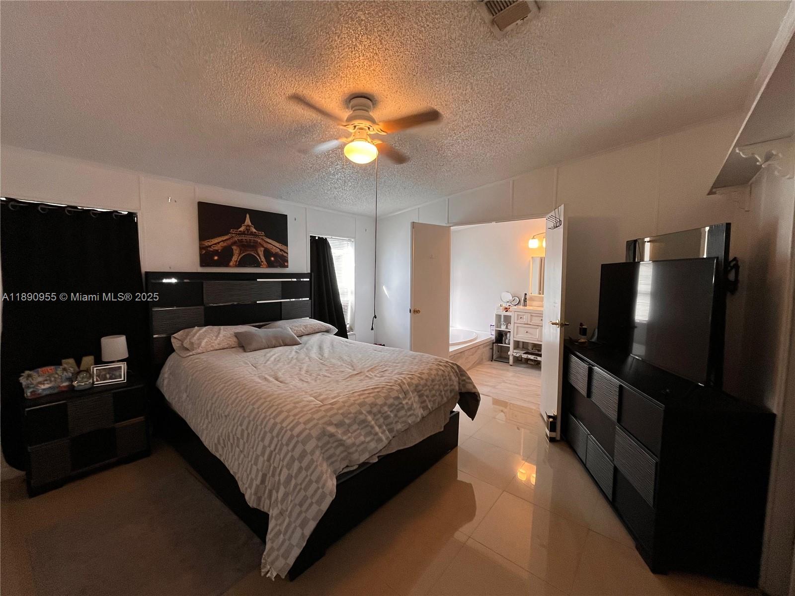 A bedroom features a bed, a dresser with a television, and an attached bathroom — 909 Sw 131 Way, Davie FL 33325, DAVIE, FL