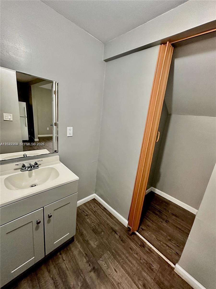 A bathroom features a gray vanity, a wall-mounted mirror, and a folding closet door — 6326 NW 4th Ave # 3, Miami FL 33150, MIAMI, FL