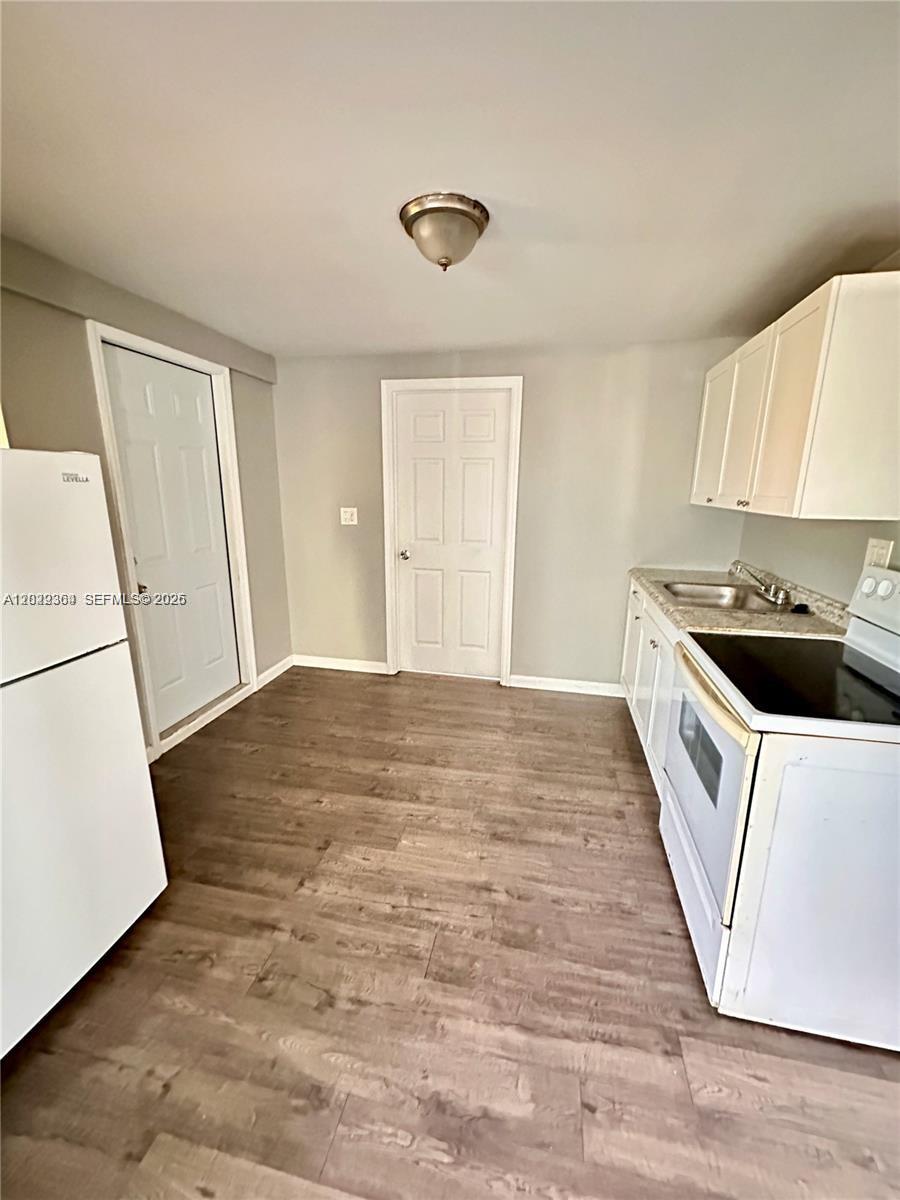 This kitchen features white cabinets, a refrigerator, a stove, and wood-look flooring — 6326 NW 4th Ave # 3, Miami FL 33150, MIAMI, FL