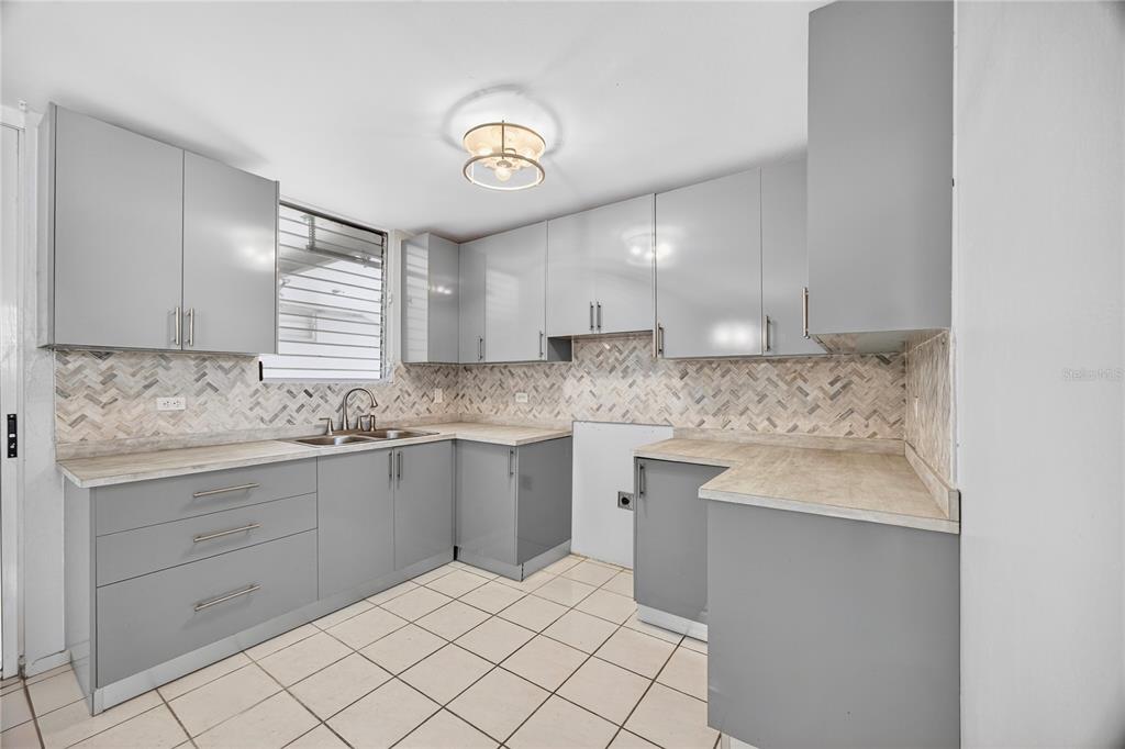 A kitchen features gray cabinets, light-colored countertops, a herringbone backsplash, and white tiled flooring — 757 ENRIQUE LAGUERRE, PONCE, PR