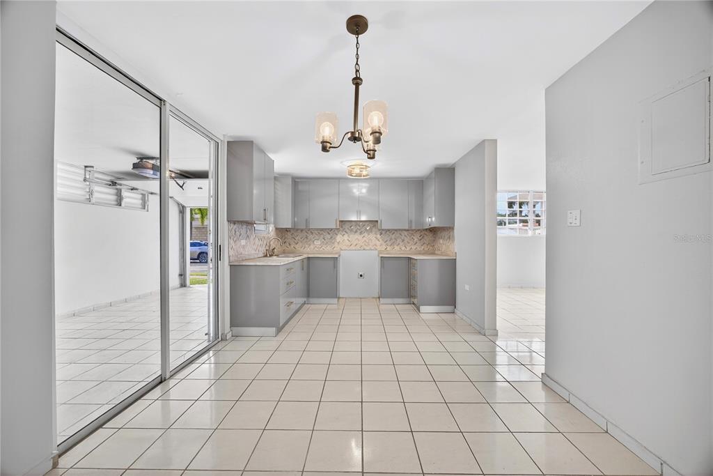 A kitchen with gray cabinets and tile flooring opens to a garage through sliding doors — 757 ENRIQUE LAGUERRE, PONCE, PR