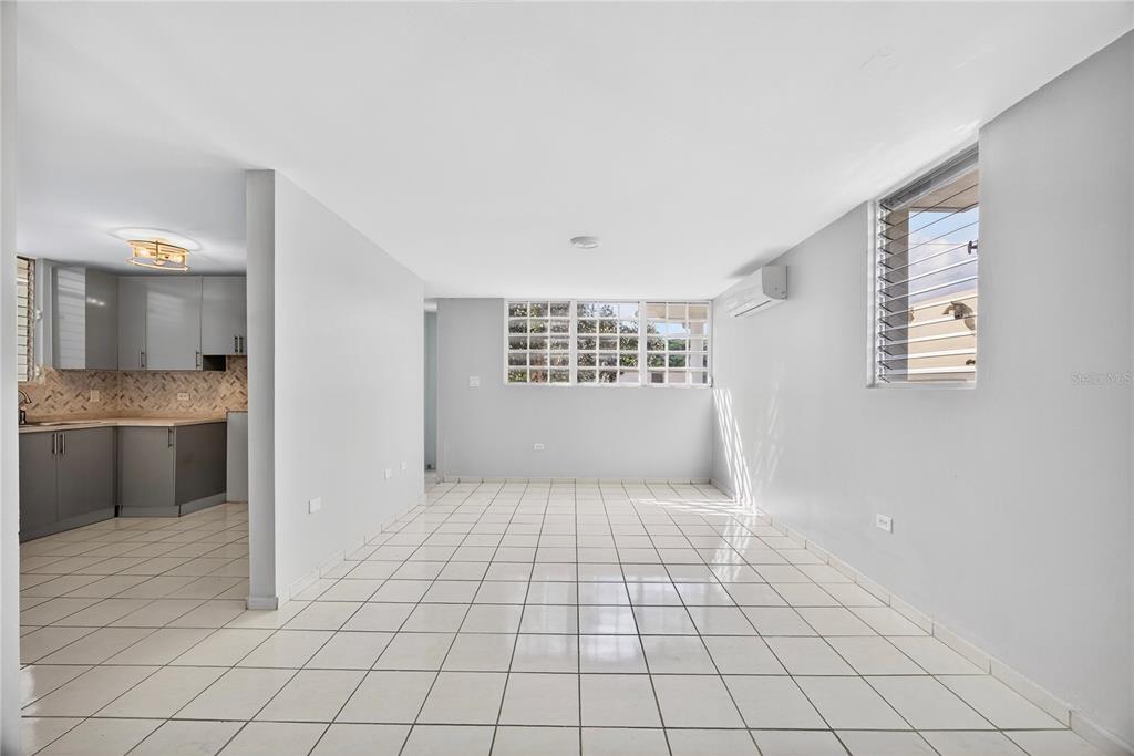 An open-concept living area with white tile flooring, gray walls, and an adjacent kitchen — 757 ENRIQUE LAGUERRE, PONCE, PR