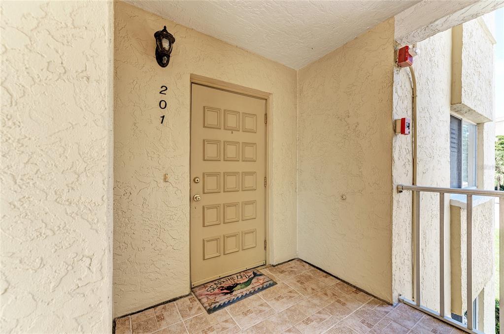 An exterior view of a tan apartment door numbered 207 with a tiled entryway — 4825 GULF OF MEXICO DRIVE UNIT 201, LONGBOAT KEY, FL