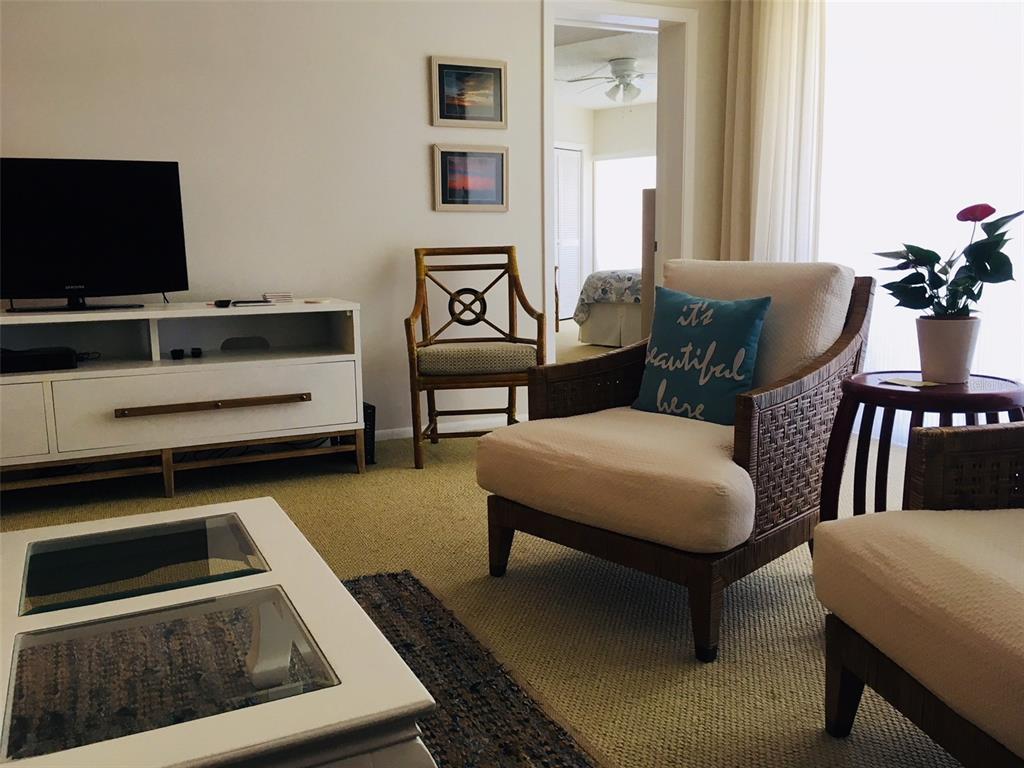 A living room features a white media console, wicker armchairs, and a glass-topped coffee table — 4825 GULF OF MEXICO DRIVE UNIT 201, LONGBOAT KEY, FL