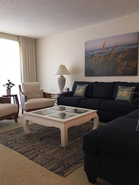 A living room features a dark blue sofa, a white coffee table, and beach-themed wall art — 4825 GULF OF MEXICO DRIVE UNIT 201, LONGBOAT KEY, FL