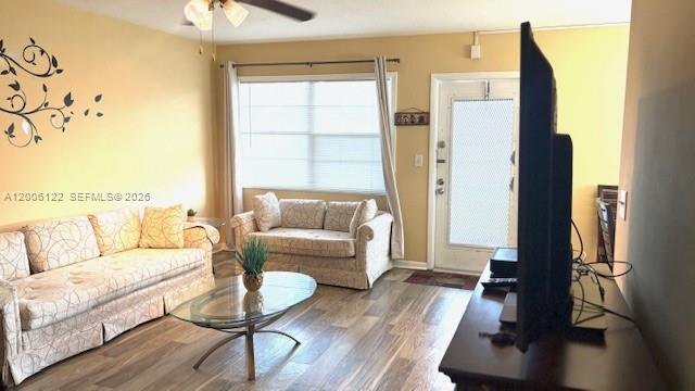 A living room features a patterned sofa, a loveseat, a glass coffee table, and wood flooring — 1044 Harwood D # D, Deerfield Beach FL 33442, DEERFIELD BEACH, FL