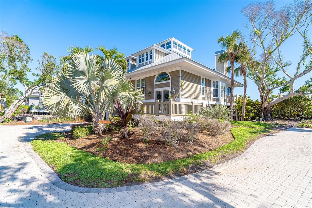 A two-story house with light brown siding and a wrap-around porch sits near palm trees — 36 SEAWATCH DRIVE, BOCA GRANDE, FL
