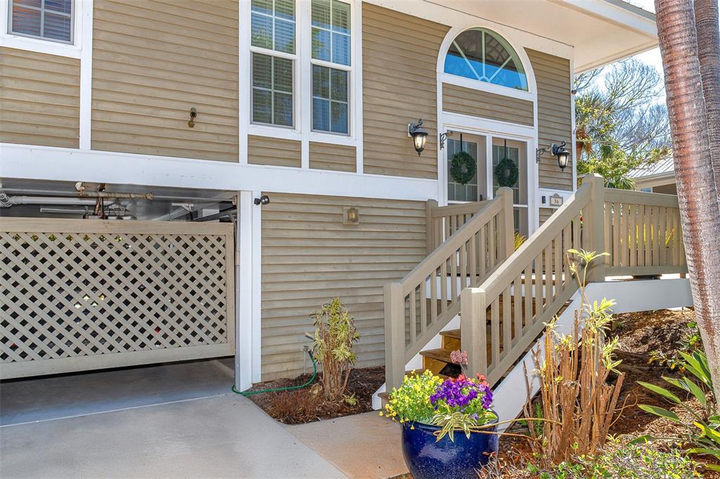 The exterior of a house features tan siding, a lattice-enclosed ground level, and wooden stairs — 36 SEAWATCH DRIVE, BOCA GRANDE, FL