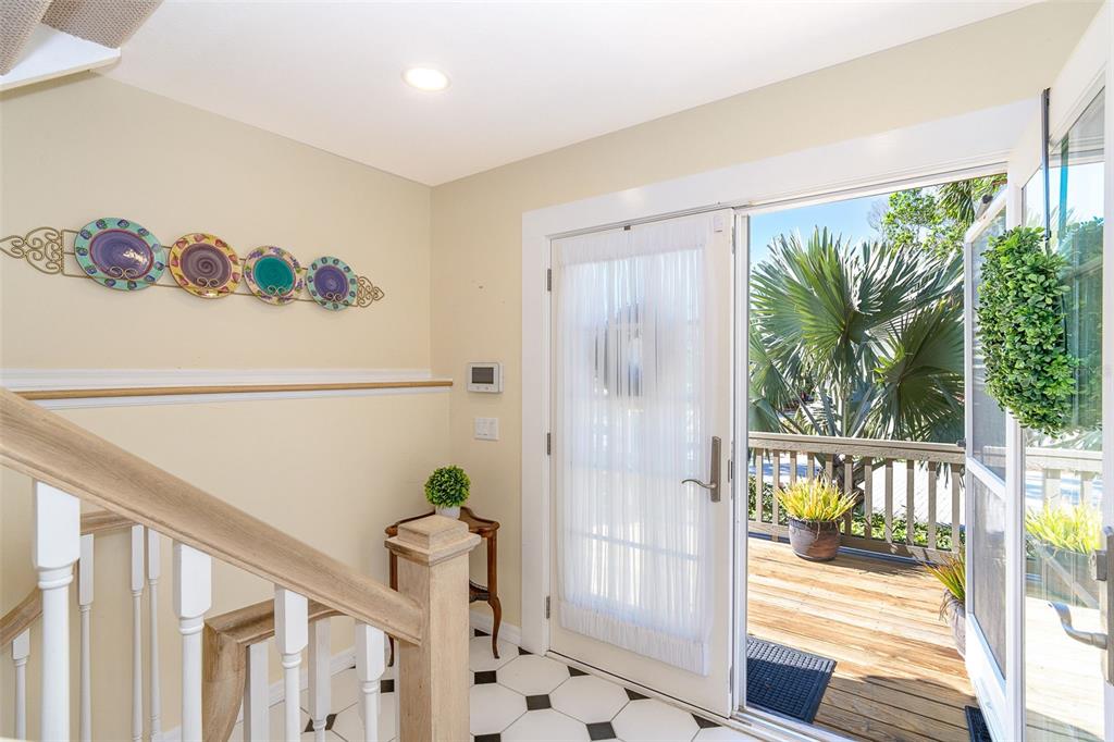 An entryway features a staircase, tiled floor, wall-mounted decorative plates, and a door opening onto a deck — 36 SEAWATCH DRIVE, BOCA GRANDE, FL