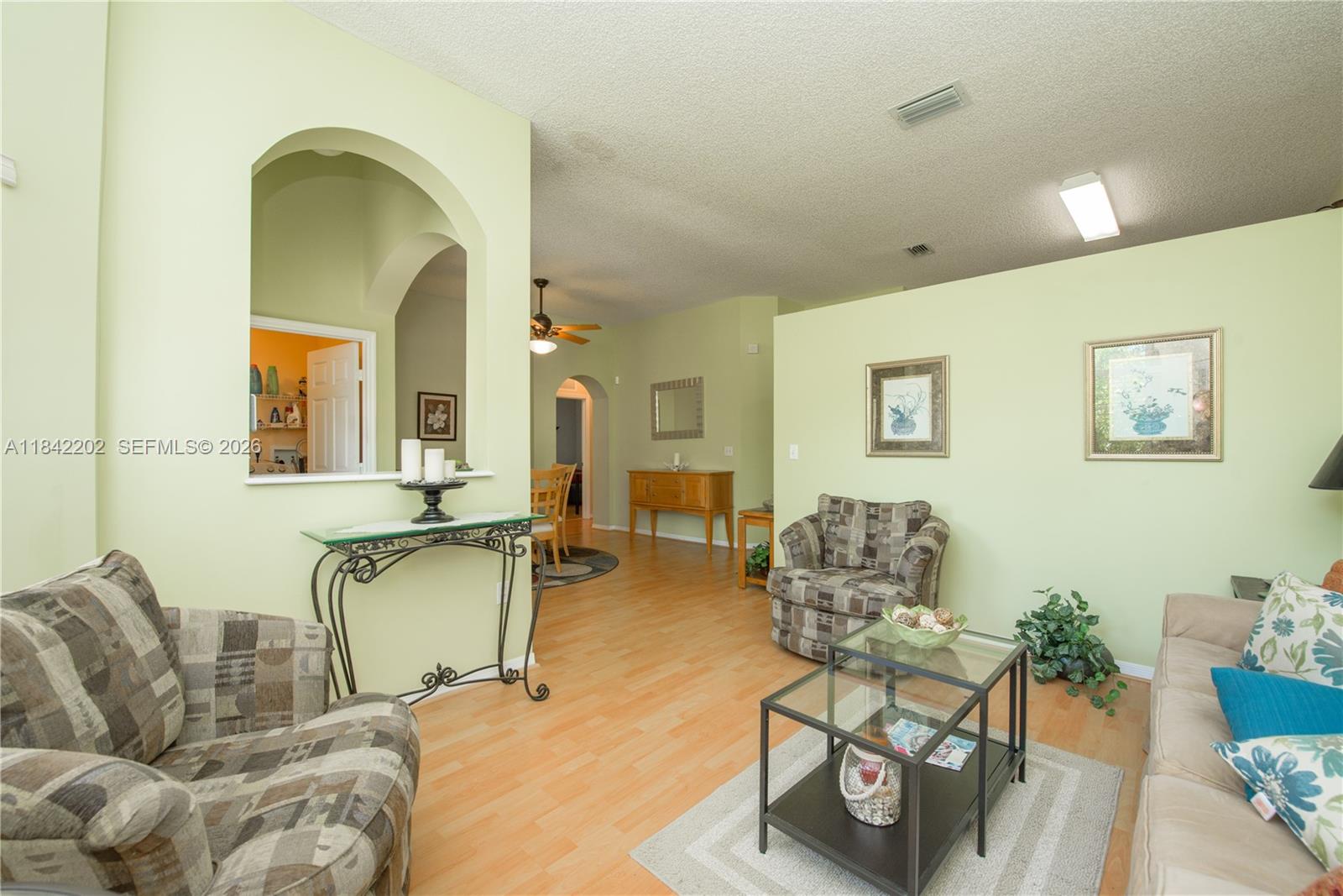 A living room features light green walls, wood-look flooring, and an arched entryway — 460 SE 24th Dr, Homestead FL 33033, HOMESTEAD, FL