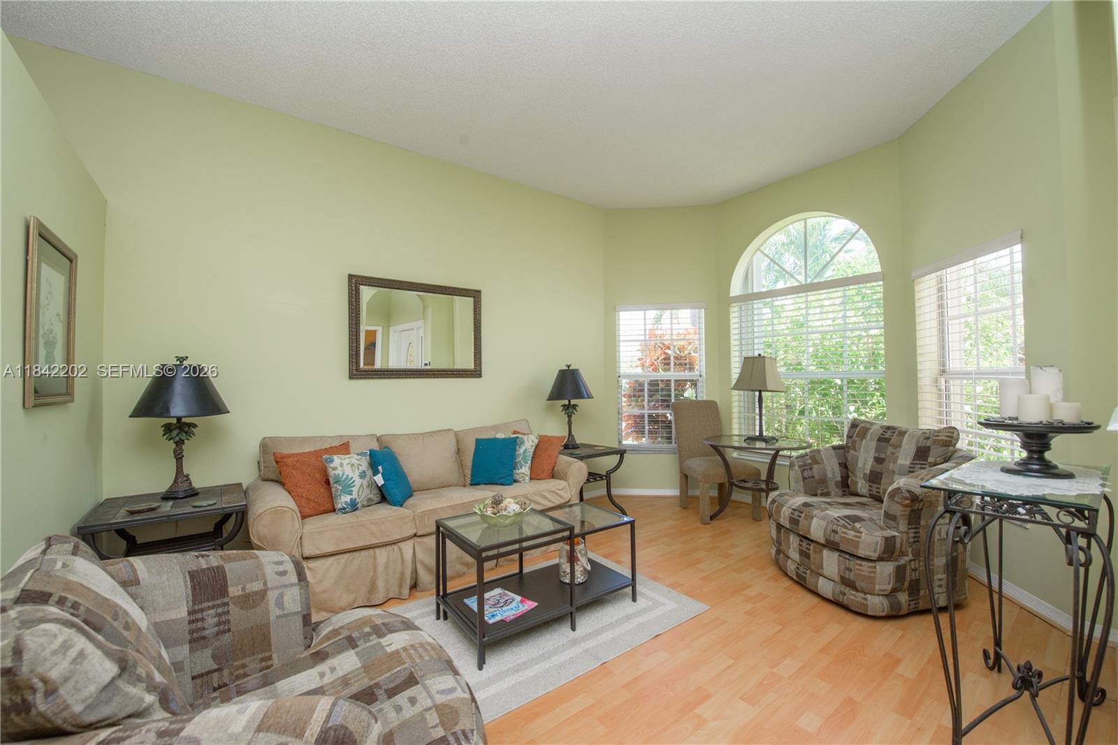 A living room features light green walls, a beige sofa, two patterned armchairs, and windows — 460 SE 24th Dr, Homestead FL 33033, HOMESTEAD, FL