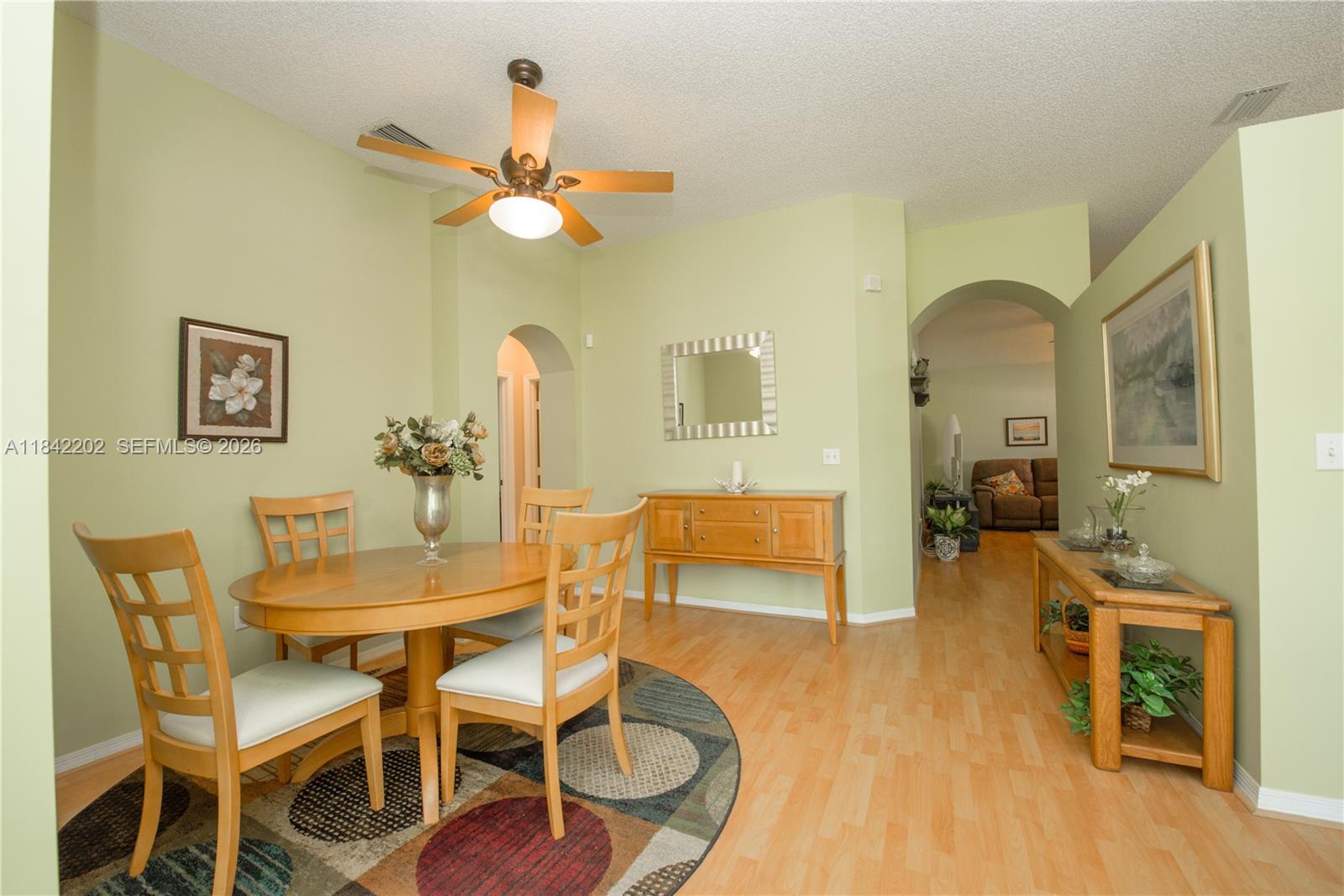 A dining room features light green walls, wood flooring, a ceiling fan, and wooden furniture — 460 SE 24th Dr, Homestead FL 33033, HOMESTEAD, FL