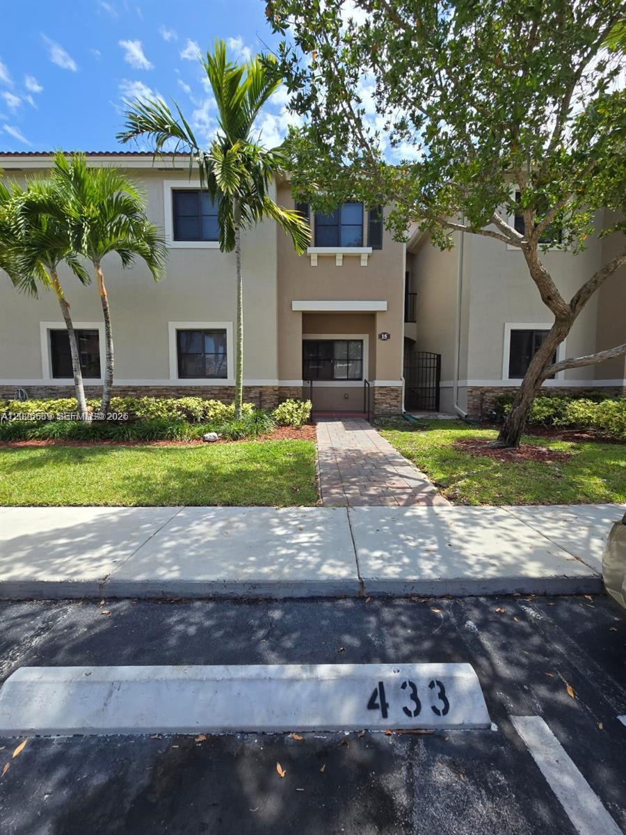 A two-story residential building exterior features a paved walkway leading to a central entrance — CUTLER BAY, FL