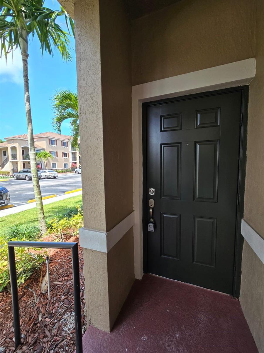 A black front door is set within a tan stucco entryway under a covered porch — CUTLER BAY, FL