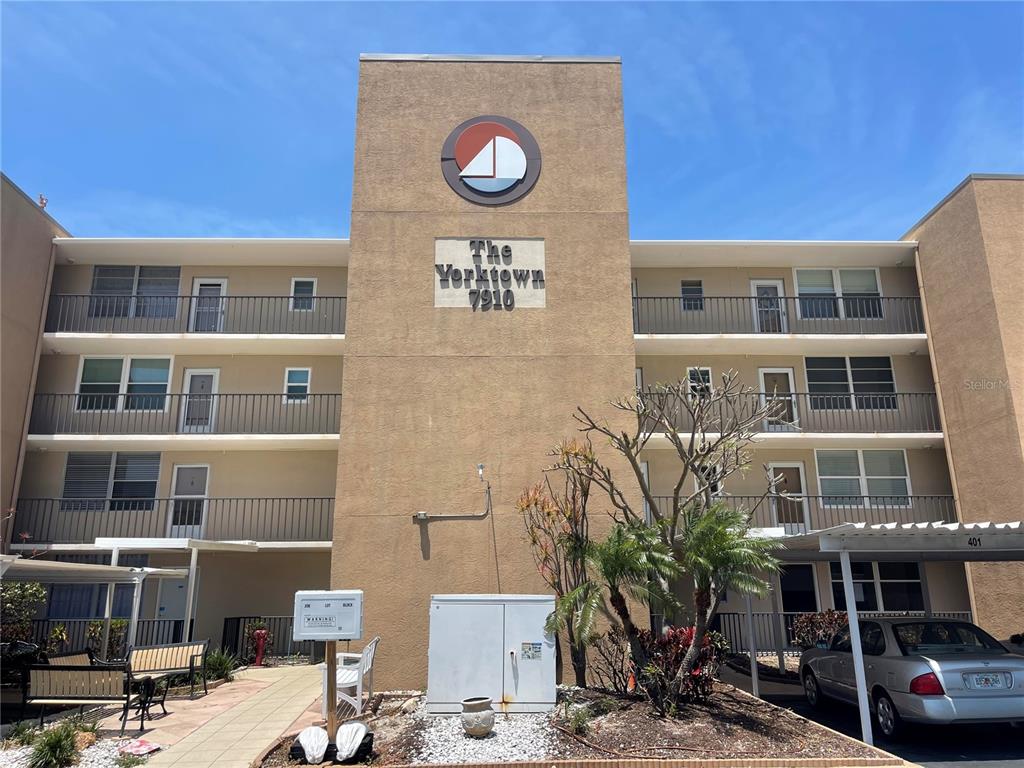 A multi-story tan apartment building features a central tower with a sailboat logo — 7910 SUN ISLAND DRIVE S UNIT 203, SOUTH PASADENA, FL