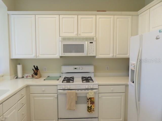 A kitchen features white cabinets, a white stove, a built-in microwave, and a white refrigerator — 9720 SEA TURTLE TERRACE UNIT 201, BRADENTON, FL