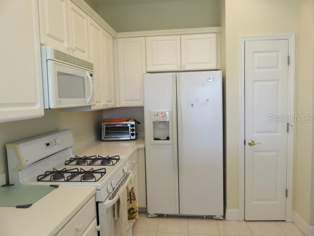 A kitchen with white cabinets, a gas range, a microwave, and a side-by-side refrigerator — 9720 SEA TURTLE TERRACE UNIT 201, BRADENTON, FL