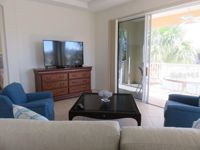 A living room features a television on a wooden dresser, a coffee table, and armchairs — 9720 SEA TURTLE TERRACE UNIT 201, BRADENTON, FL