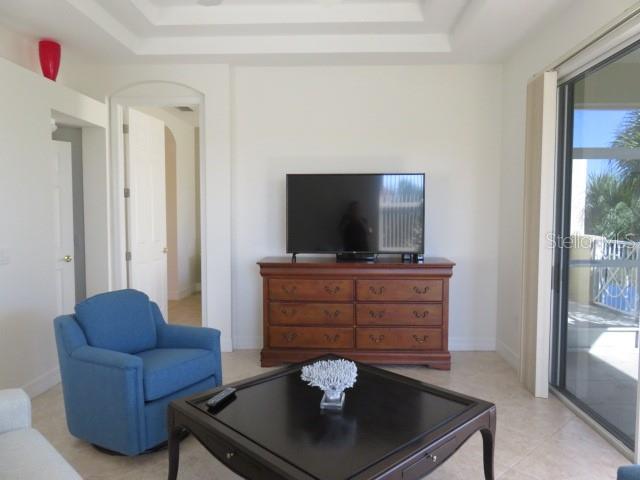 A living room features a blue armchair, a dark coffee table, and a television on a dresser — 9720 SEA TURTLE TERRACE UNIT 201, BRADENTON, FL