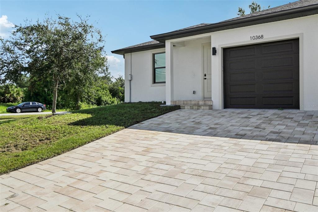 A single-story house features a paved driveway, a dark garage door, and a white exterior — 10368 PORT EVERGLADES STREET, PORT CHARLOTTE, FL