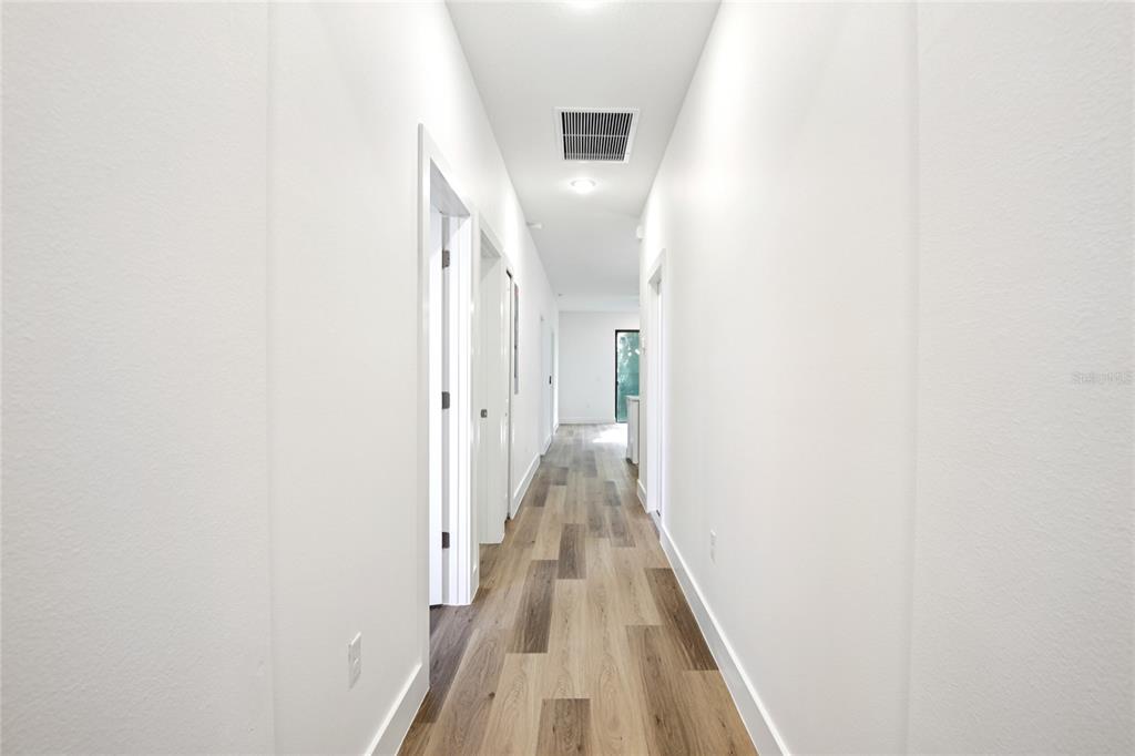 A bright hallway features white walls, light wood-look flooring, and several doorways — 10368 PORT EVERGLADES STREET, PORT CHARLOTTE, FL