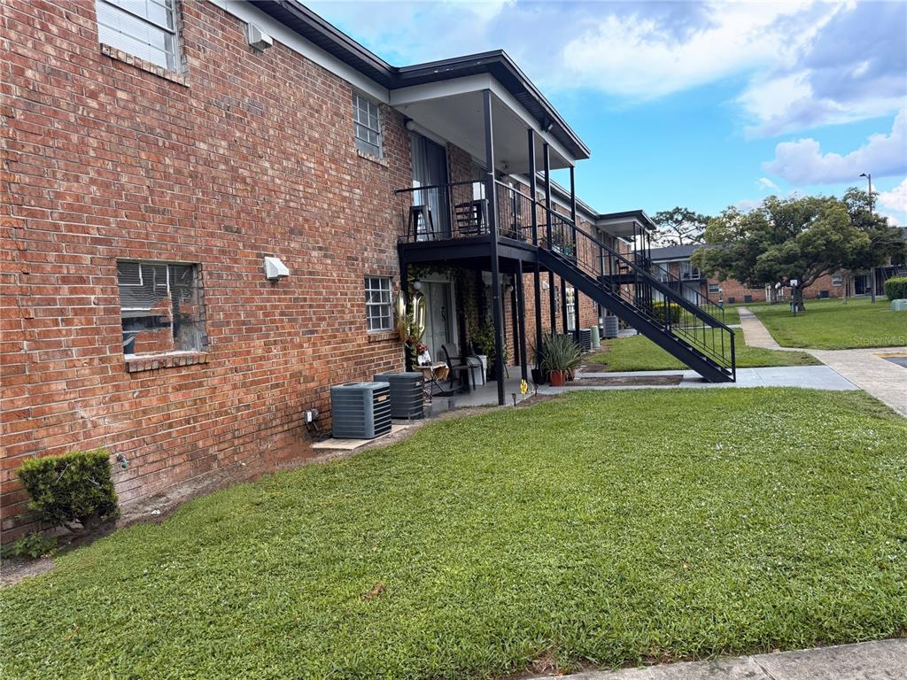 A two-story brick apartment building features an exterior metal staircase and a ground-level patio — 5325 CURRY FORD ROAD UNIT G202, ORLANDO, FL
