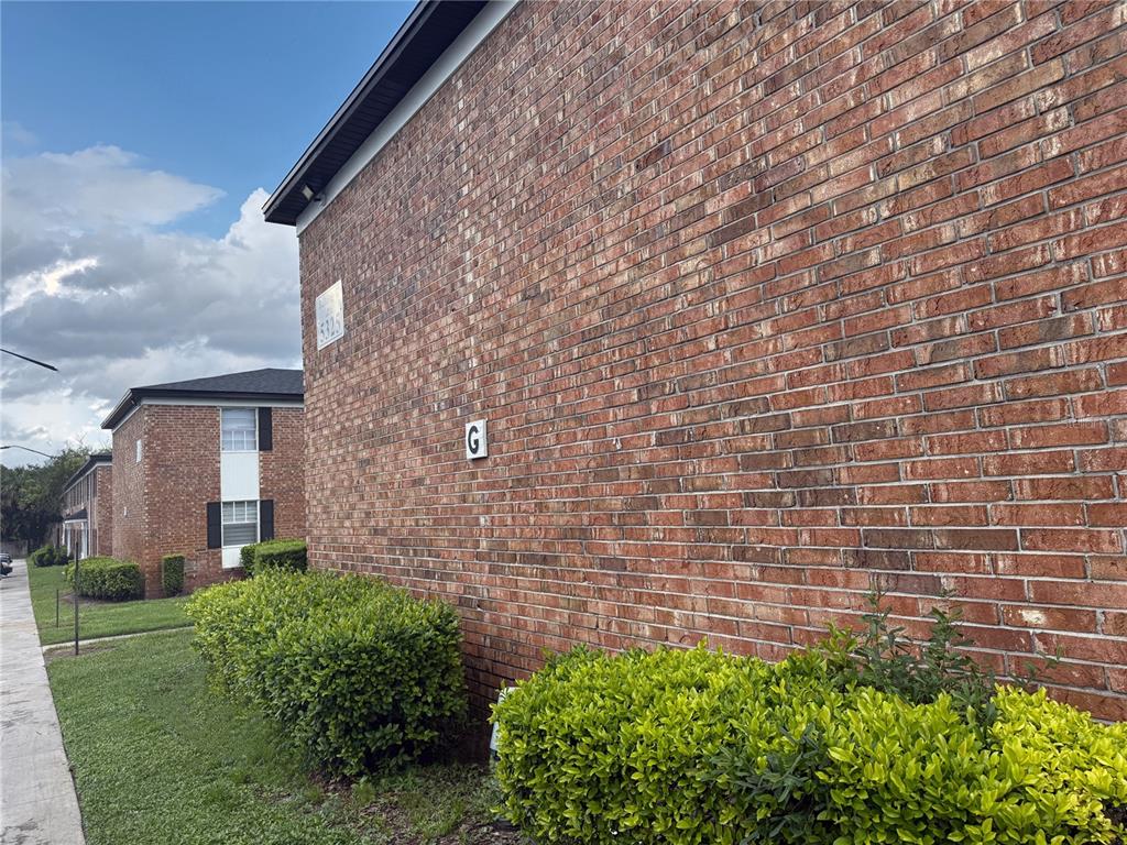 A side view of a brick apartment building with a letter G sign and landscaping — 5325 CURRY FORD ROAD UNIT G202, ORLANDO, FL