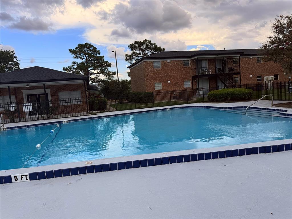 A swimming pool with a depth marker sits in front of brick apartment buildings — 5325 CURRY FORD ROAD UNIT G202, ORLANDO, FL