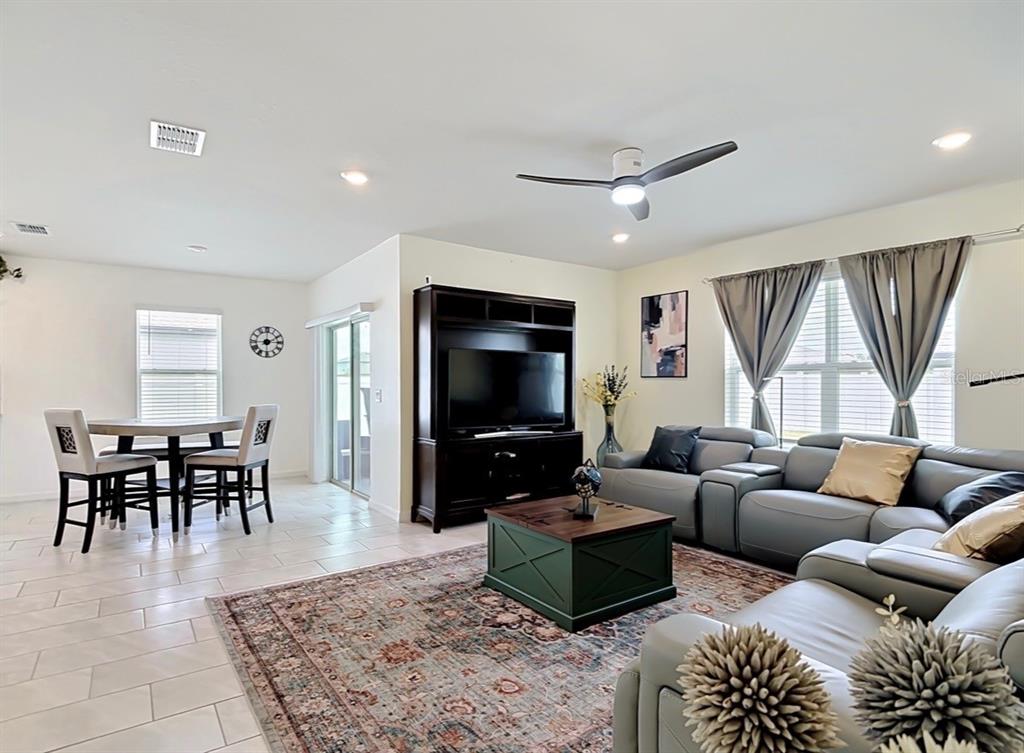 A living room with a grey sectional, dark wood entertainment center, and a dining area — 1059 MICHELANGELO LANE, WINTER HAVEN, FL