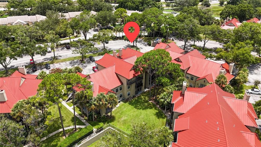 An aerial view shows a multi-story apartment complex with red metal roofs and landscaping — 232 AFTON SQUARE UNIT 108, ALTAMONTE SPRINGS, FL