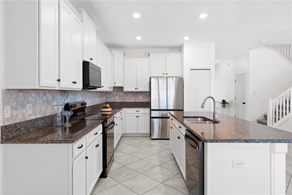 A kitchen features white cabinets, granite countertops, stainless steel appliances, and a tiled floor — 11411 CHILLY WATER COURT, RIVERVIEW, FL