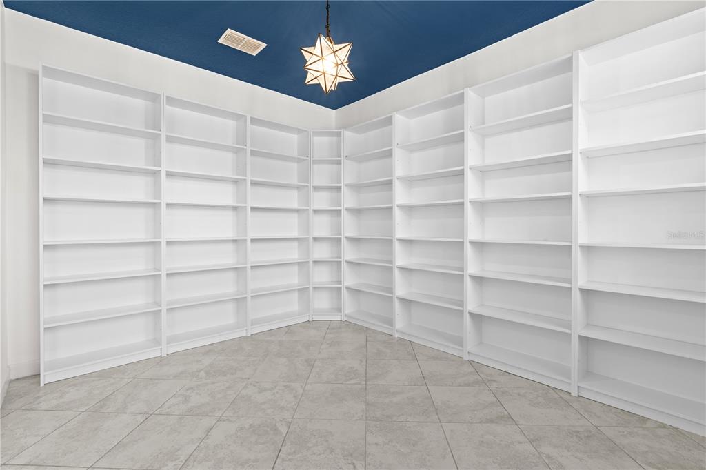A room with white built-in bookshelves, tiled floors, and a blue ceiling with a pendant light — 11411 CHILLY WATER COURT, RIVERVIEW, FL