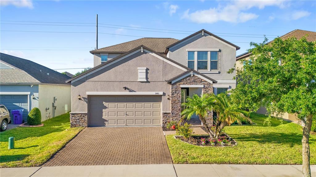 A two-story suburban house features a stone-accented entryway, a paved driveway, and a garage — 11411 CHILLY WATER COURT, RIVERVIEW, FL