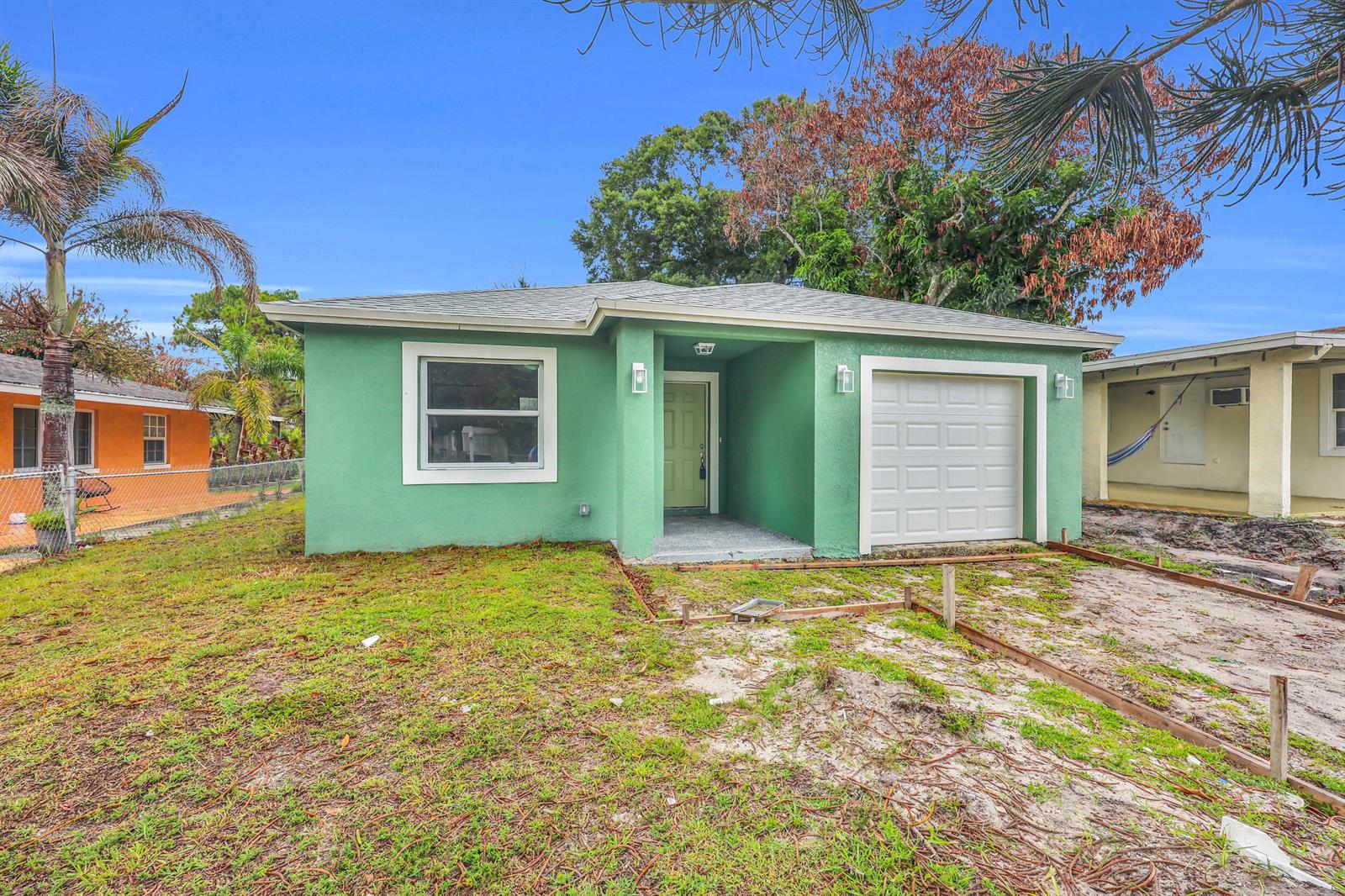 A single-story green house with a white garage door and a front yard under construction — 2002 Avenue M, Fort Pierce FL 34950, FORT PIERCE, FL