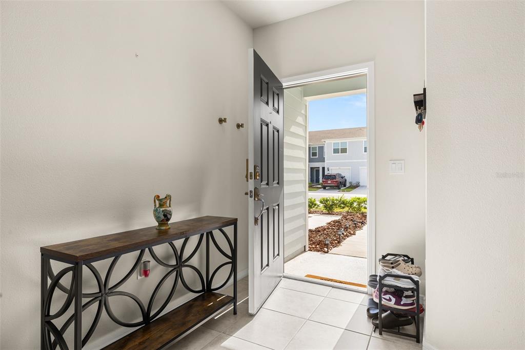 An entryway features a console table, a shoe rack, and an open door to outside — 2706 FETCHING TRAIL, DAVENPORT, FL