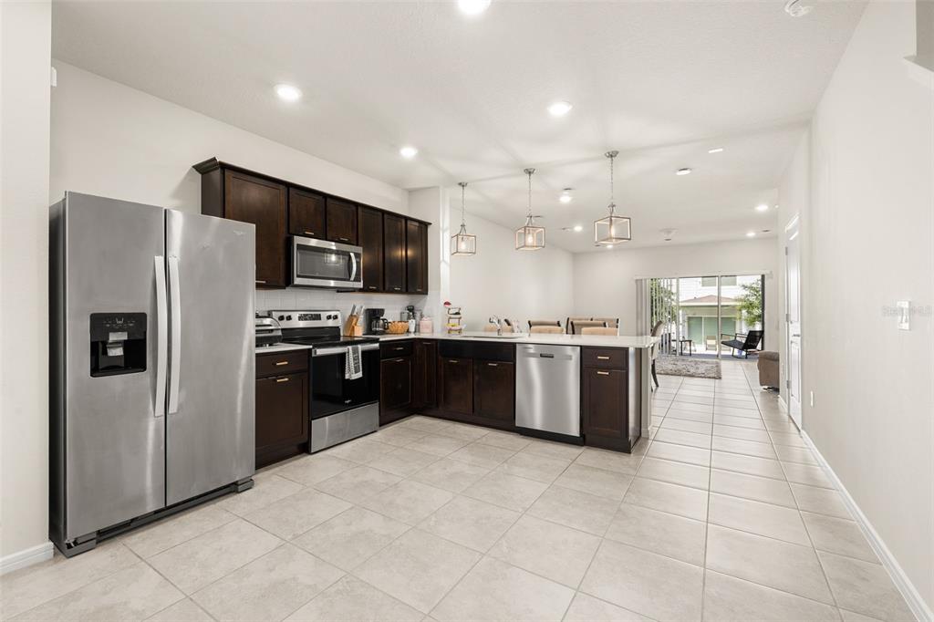 A kitchen with dark wood cabinets, stainless steel appliances, and tile flooring — 2706 FETCHING TRAIL, DAVENPORT, FL