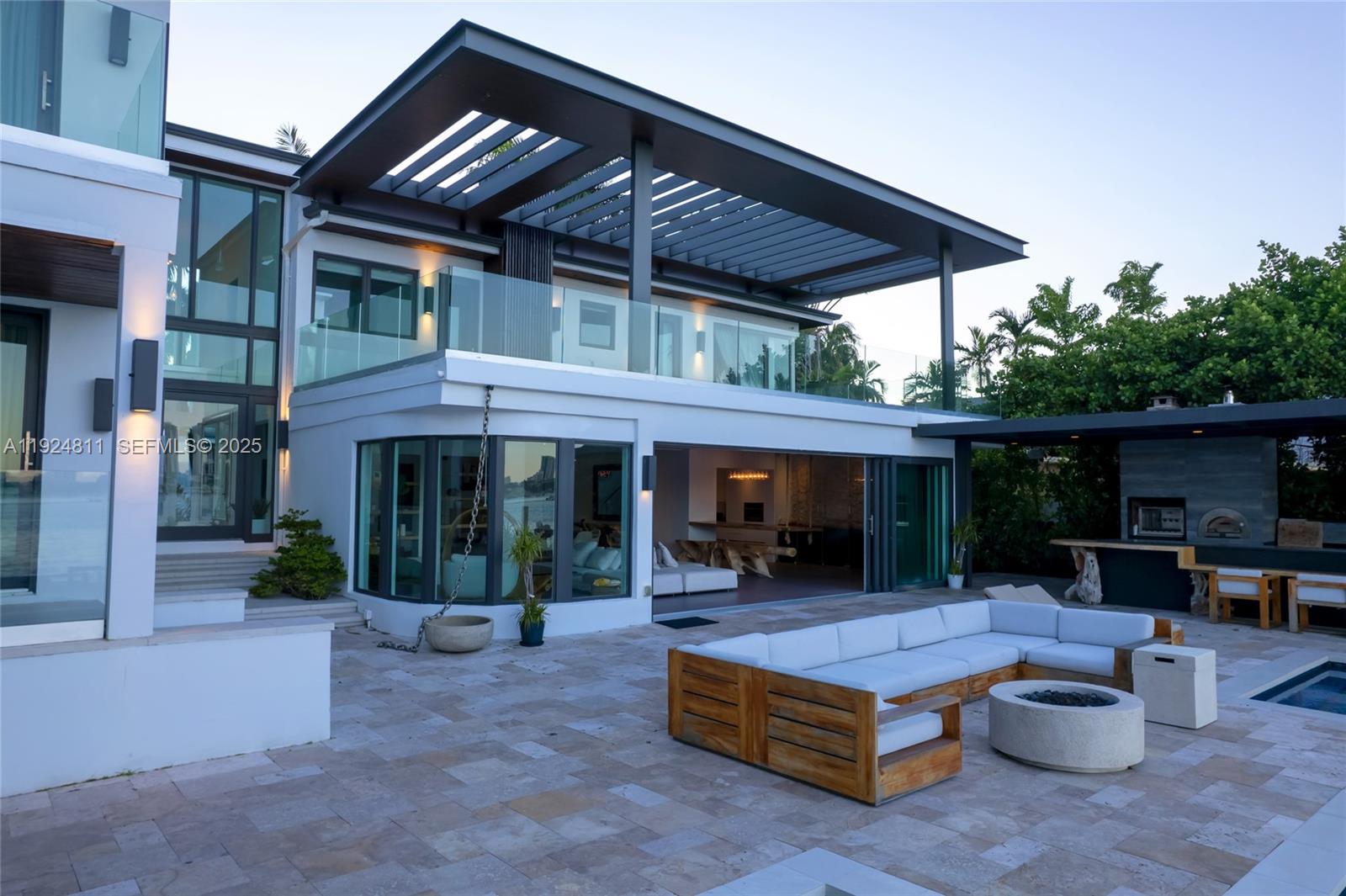 A modern patio features a large sectional sofa, a fire pit, and an outdoor kitchen — 327 E Rivo Alto Dr, Miami Beach FL 33139, MIAMI BEACH, FL