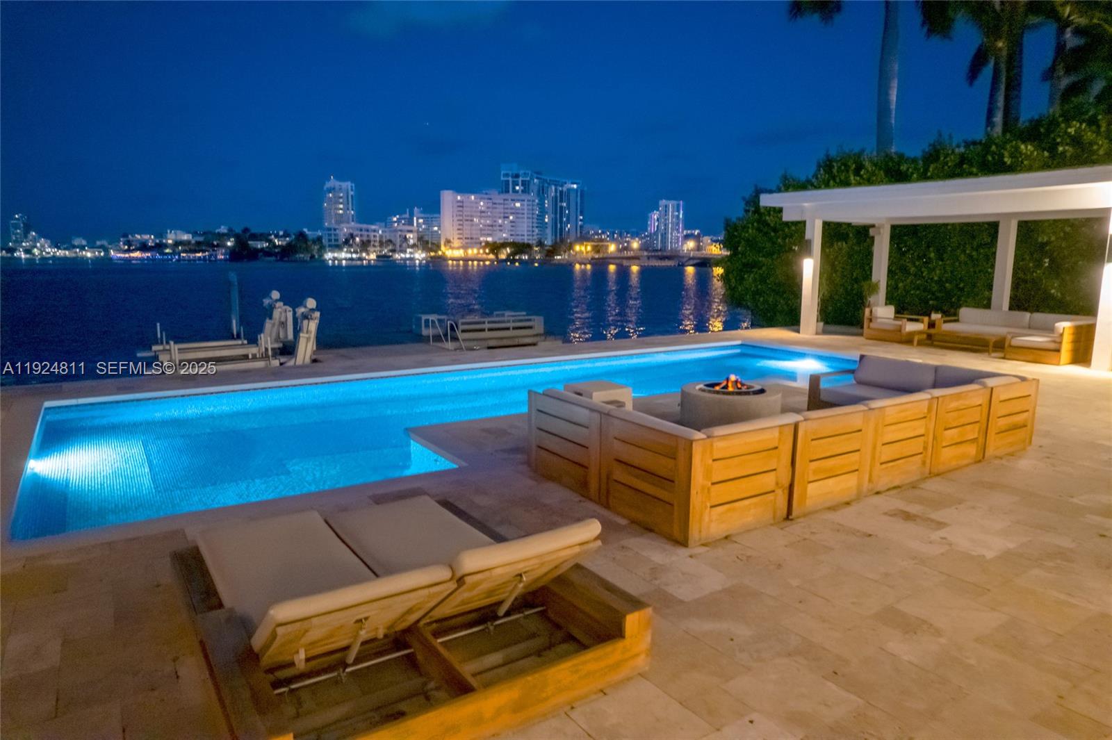An outdoor patio features a swimming pool, lounge seating, and a fire pit at night — 327 E Rivo Alto Dr, Miami Beach FL 33139, MIAMI BEACH, FL