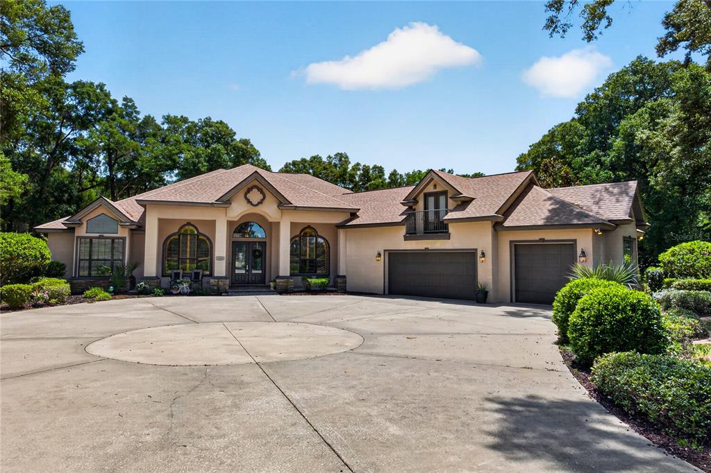 A single-story house with a beige stucco exterior, a large concrete driveway, and attached garages — 1640 SE 91ST PLACE, OCALA, FL
