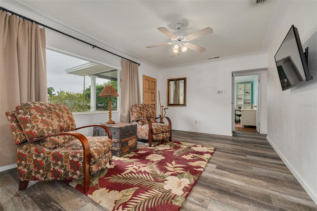 A living room features patterned armchairs, a floral rug, wood-look flooring, and a ceiling fan — 4200 29TH AVENUE N, ST PETERSBURG, FL
