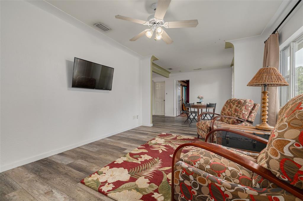 A living room with wood-look flooring, a floral area rug, and two patterned armchairs — 4200 29TH AVENUE N, ST PETERSBURG, FL