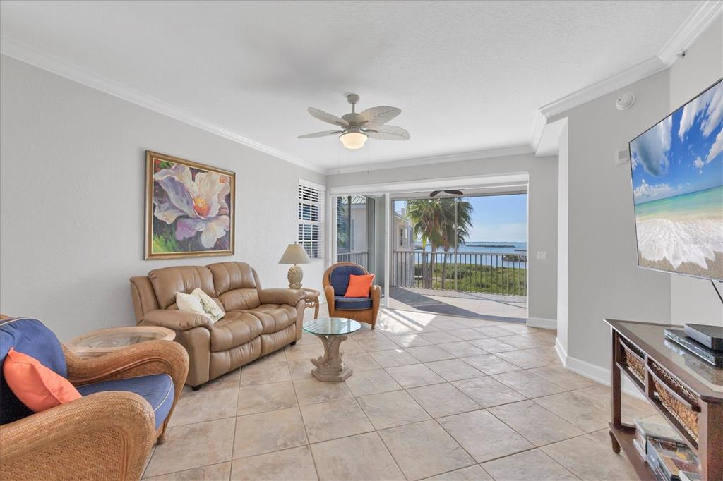 A living room with tile floors, a leather sofa, wicker chairs, and a balcony view — 13313 GASPARILLA ROAD UNIT C401, PLACIDA, FL