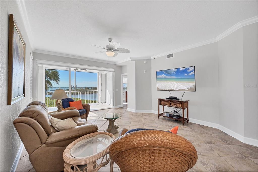 A living room features tile flooring, a leather sofa, wicker furniture, and a balcony view — 13313 GASPARILLA ROAD UNIT C401, PLACIDA, FL