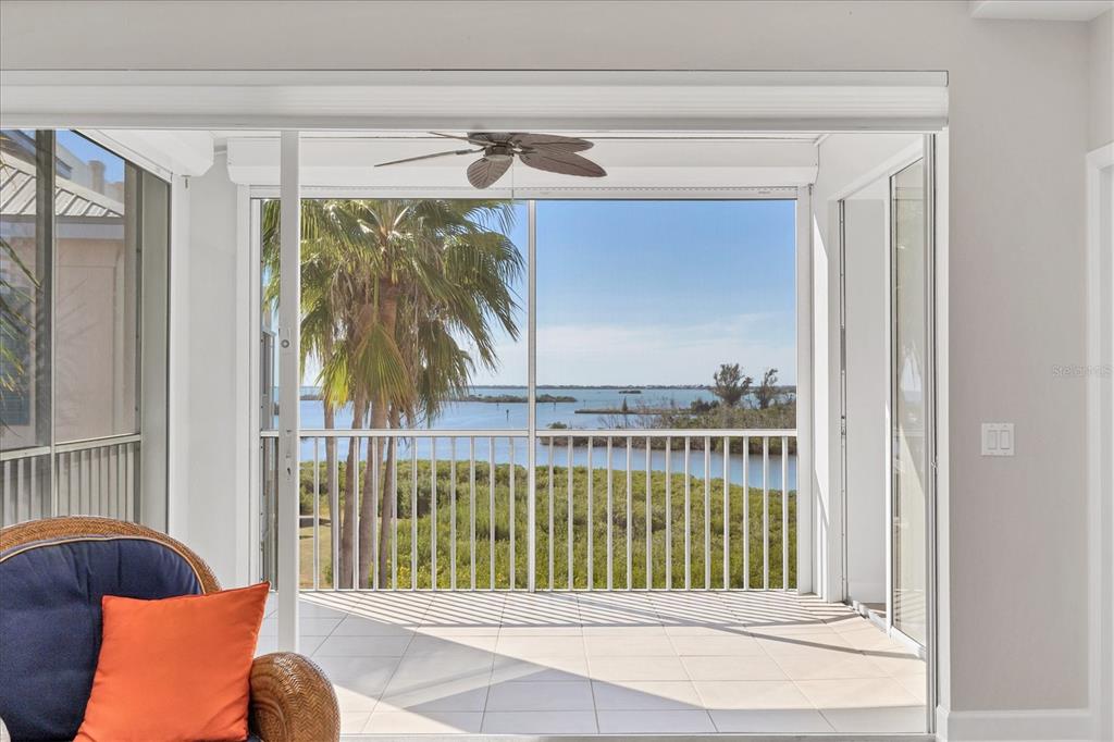 A tiled balcony with a ceiling fan overlooks a body of water and palm trees — 13313 GASPARILLA ROAD UNIT C401, PLACIDA, FL