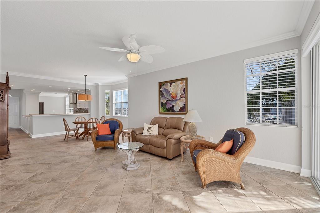 A living room with tile floors, a tan loveseat, wicker chairs, and a dining area — 13313 GASPARILLA ROAD UNIT C401, PLACIDA, FL