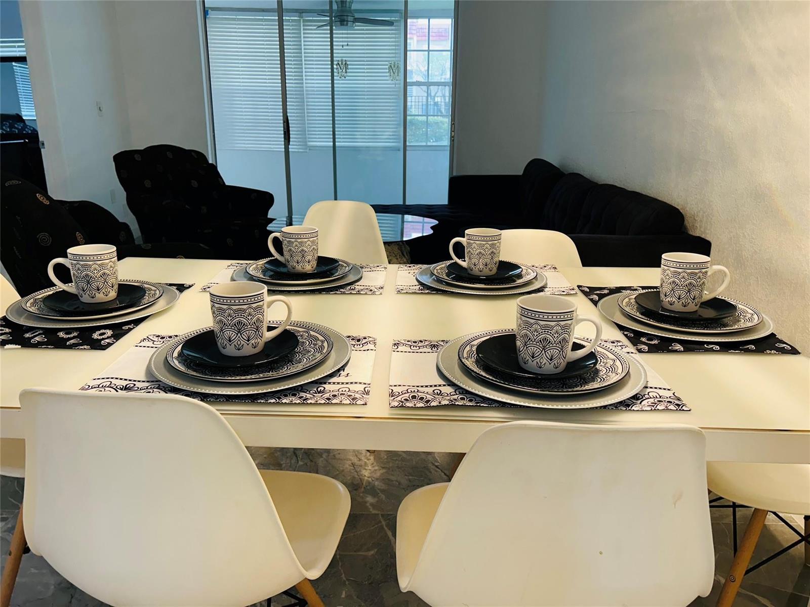 A dining room features a white table set for six with patterned mugs and plates — 2871 E Sunrise Lakes Drive # 101, Sunrise FL 33322, SUNRISE, FL