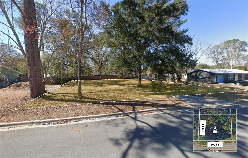 A vacant residential lot with trees is bordered by a street and neighboring houses — NW 29TH TERRACE, GAINESVILLE, FL