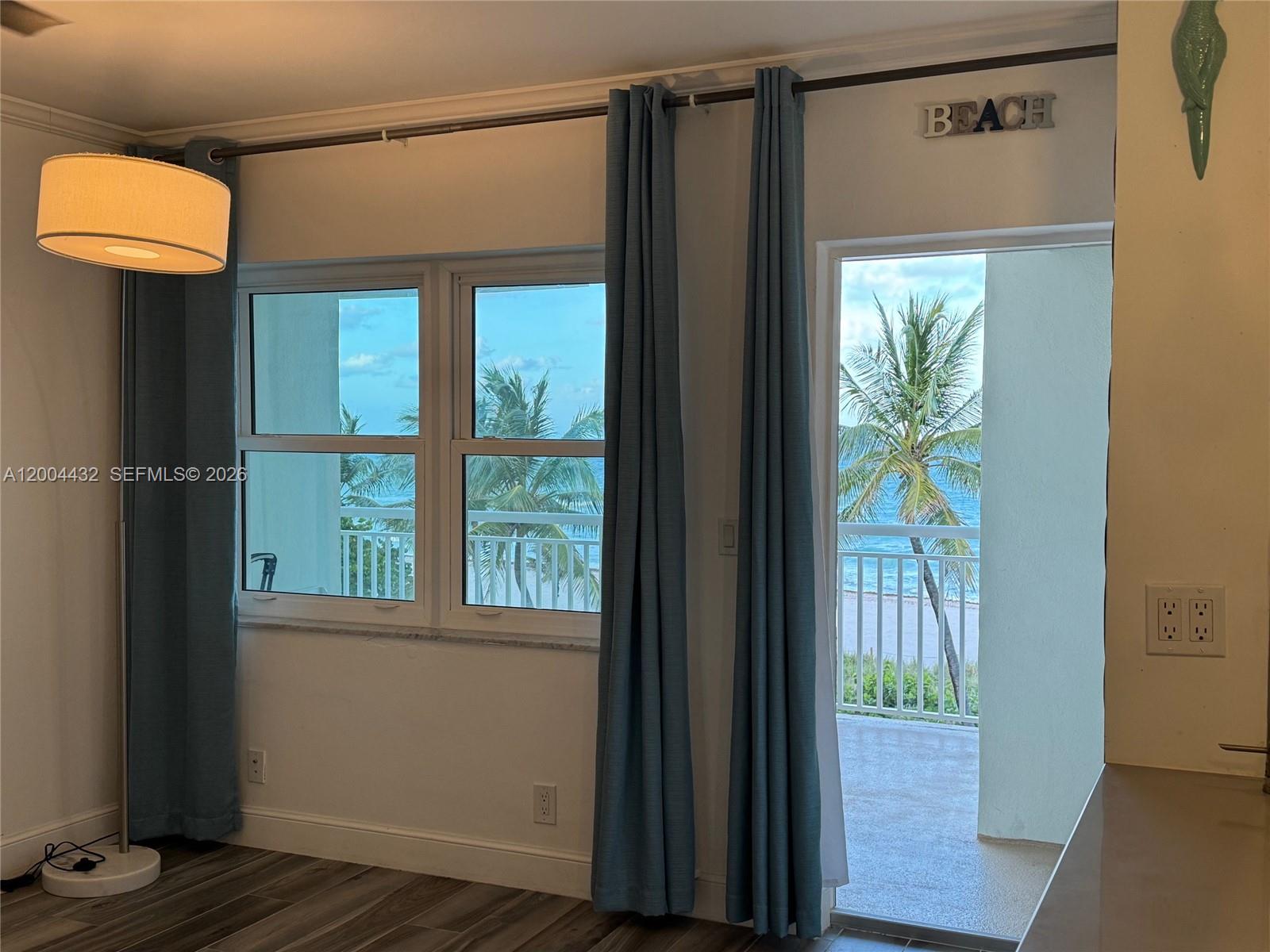 A room with blue curtains, a floor lamp, and a balcony overlooking the ocean — 901 S Surf Rd # 407, Hollywood FL 33019, HOLLYWOOD, FL